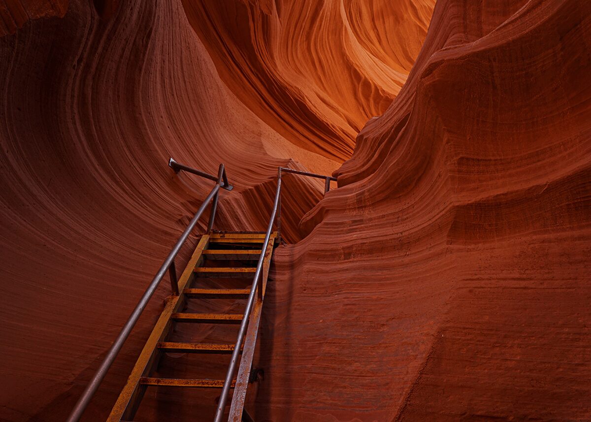 Steel stairs with handrails climbing through the curving sandstone of Lower Antelope Canyon